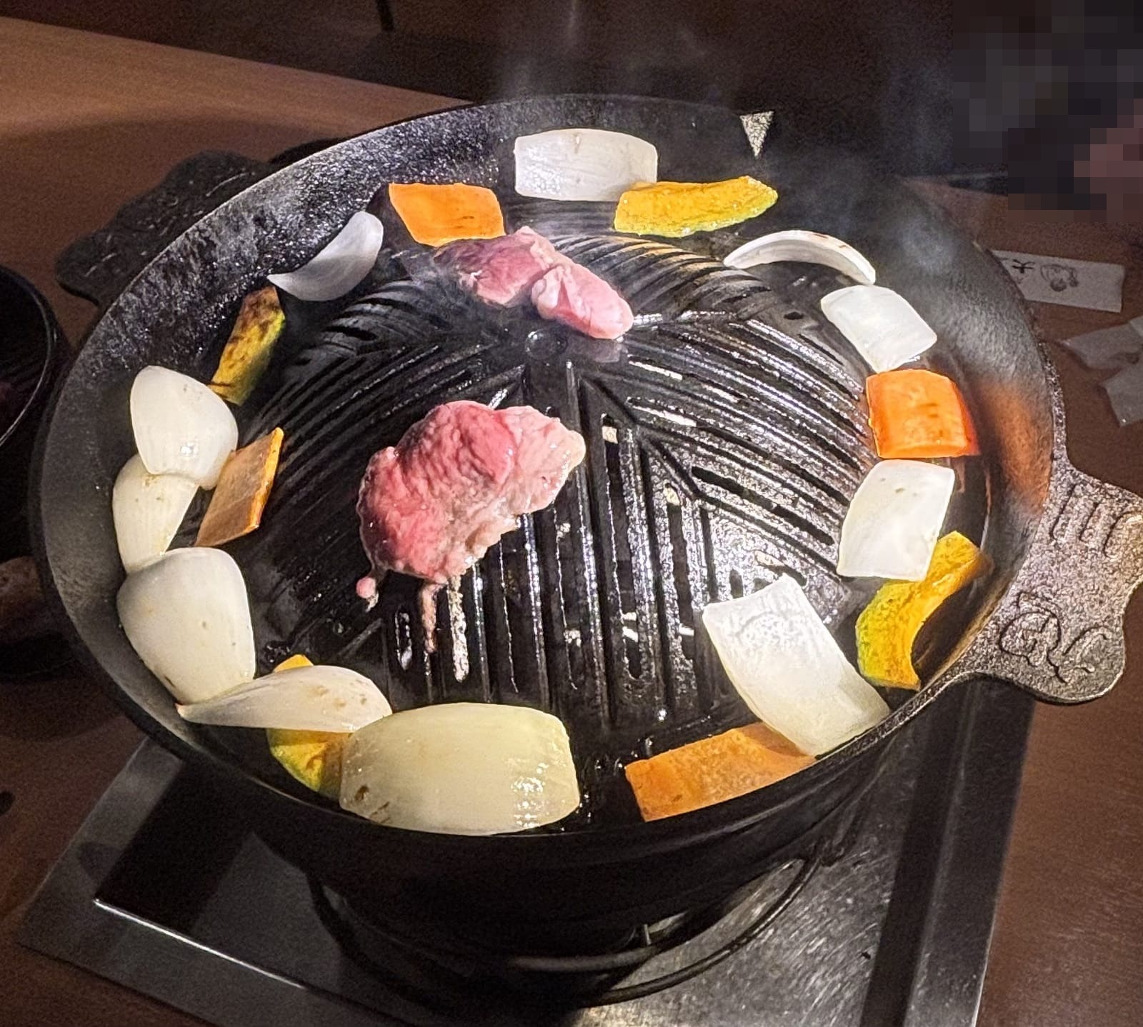 大黒屋 ジンギスカン鍋で生ラムを焼いている様子 赤みの残る焼き加減