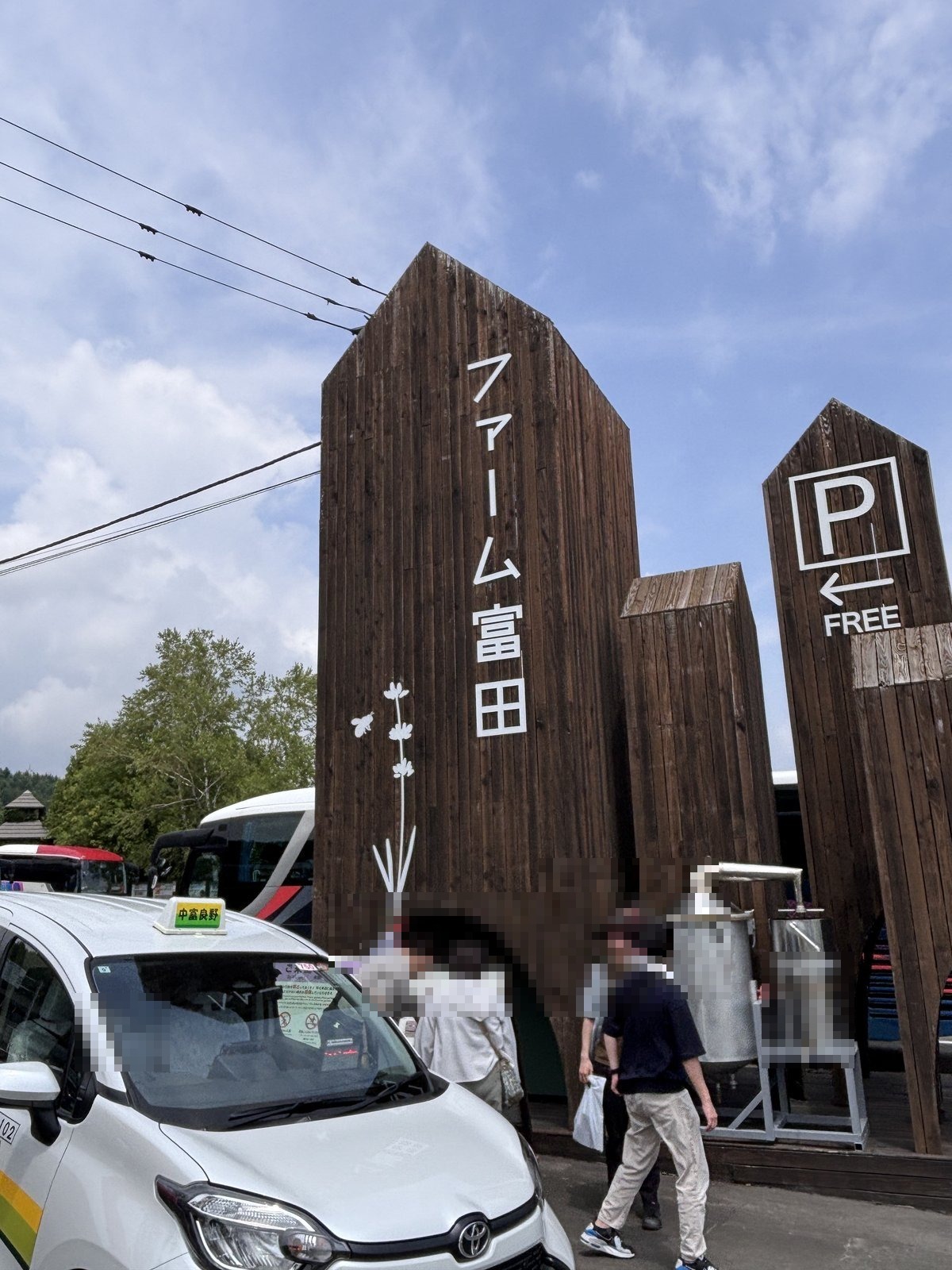 ファーム富田の入り口にある木製の大きな看板と無料駐車場の案内