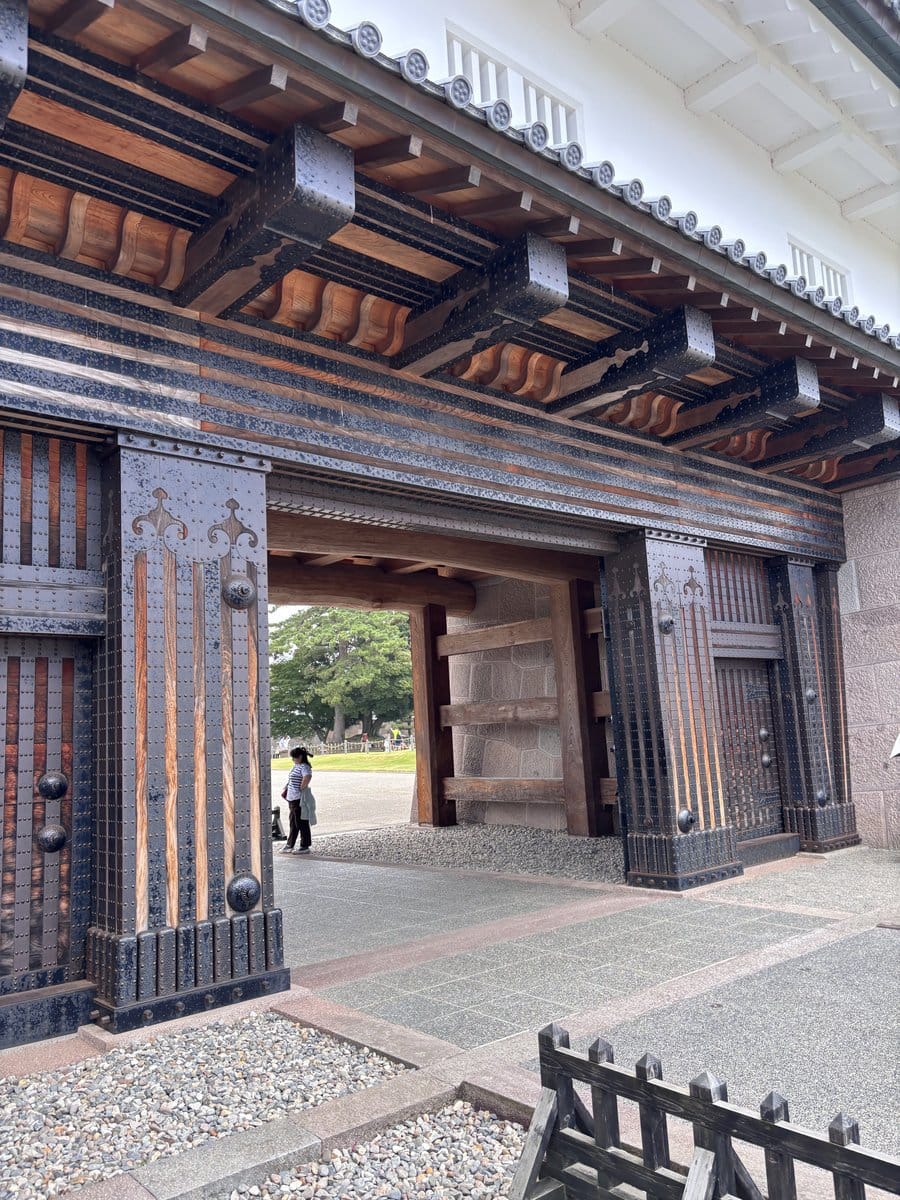 金沢城公園の石垣と重厚な木造の城門、奥に見える広場