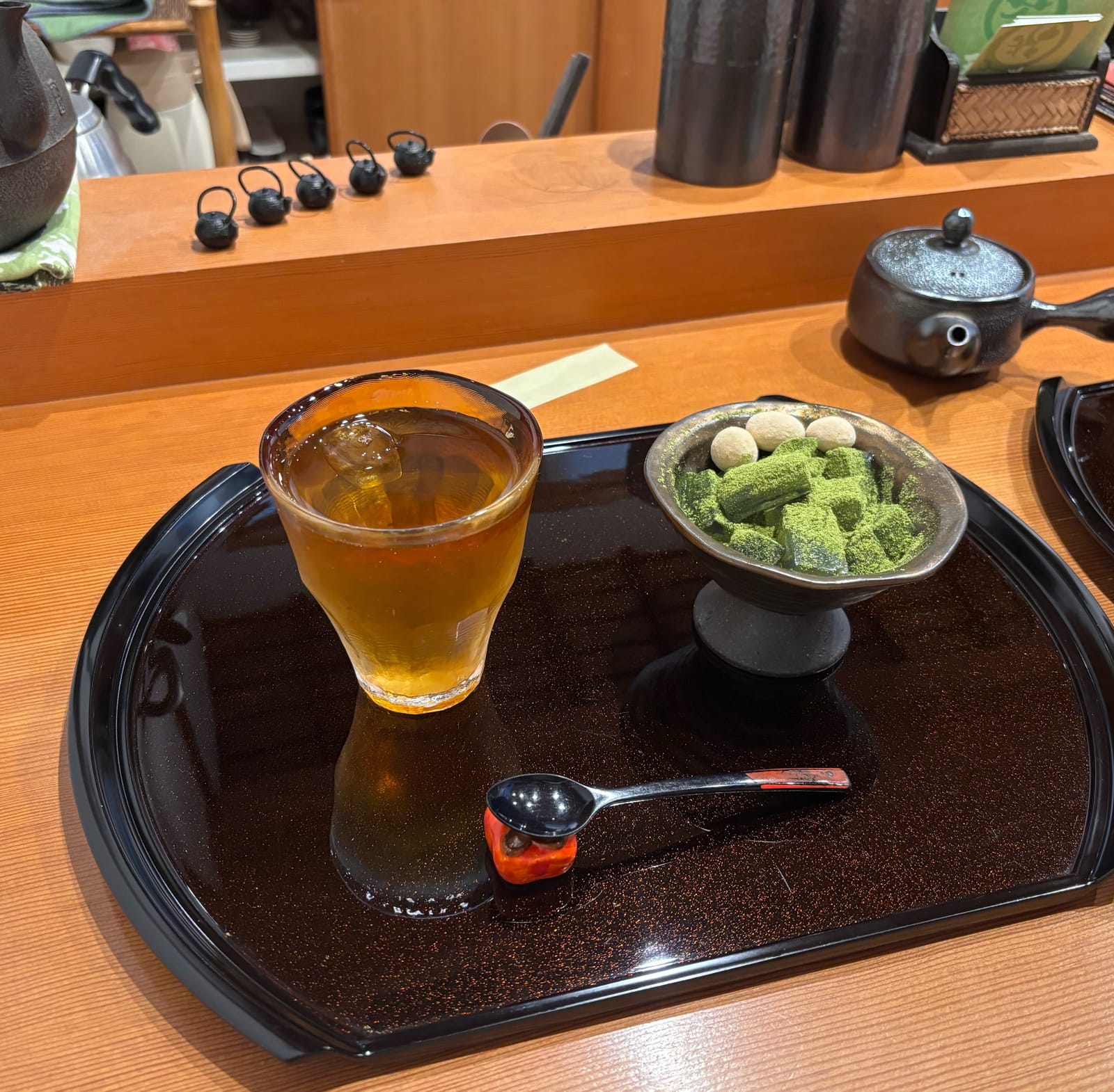 漆塗りのトレーに乗った加賀棒茶のアイスドリンクと抹茶がまぶされた水わらび餅