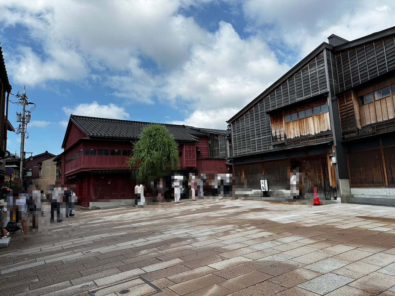 ひがし茶屋街のメイン通りに並ぶ赤い塗装の建物と柳の木、観光客の様子
