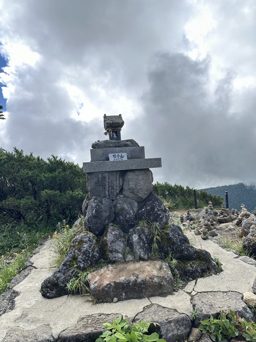 横手山山頂の標高2307mを示す石碑と周囲の石積み