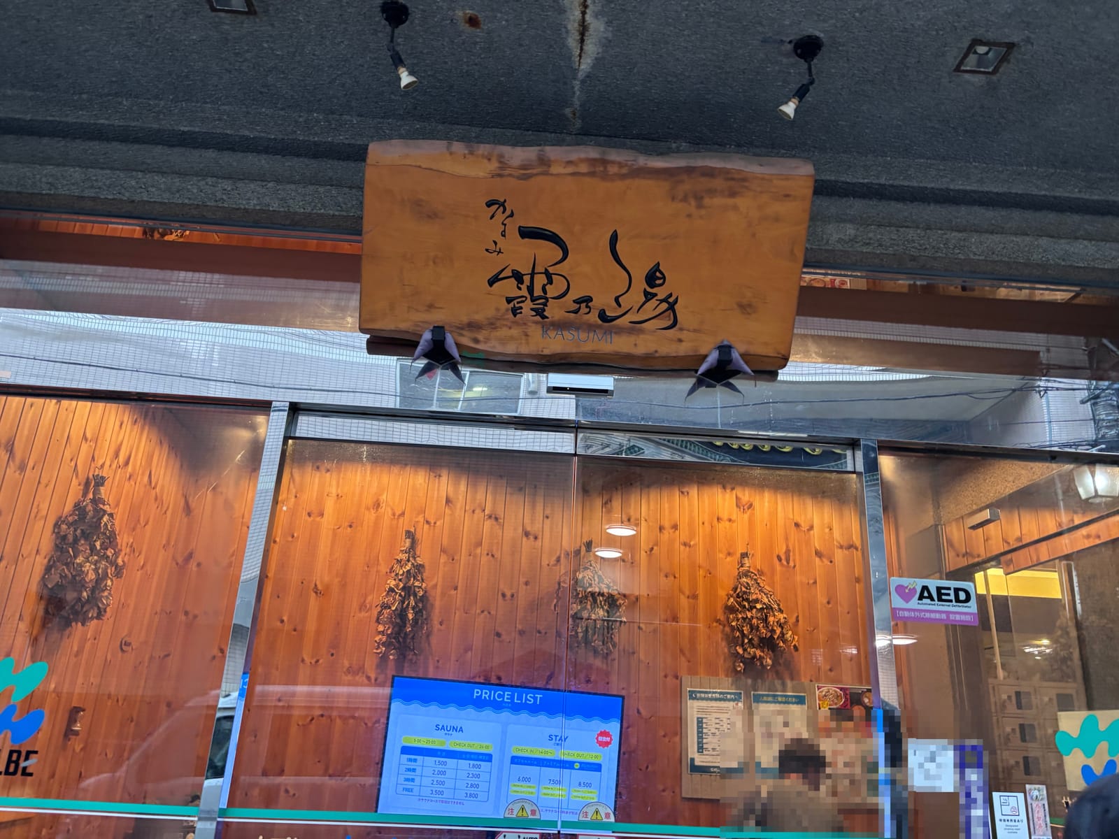 ウェルビー今池の入口 霞乃湯の木製看板と日帰りサウナの料金表